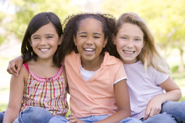 三个年轻的女孩朋友坐在户外微笑 — 图库照片