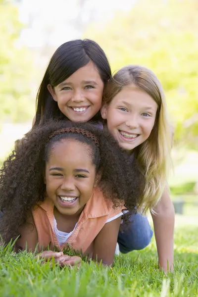 Three young girl friends piled up on top of each other outdoors — Stock Photo, Image