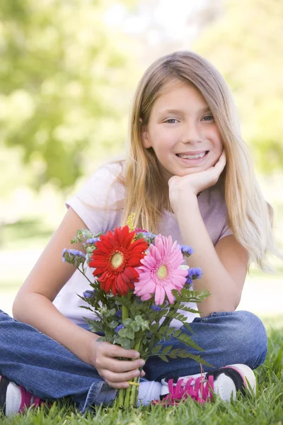 Νεαρή κοπέλα κρατώντας λουλούδια και χαμογελαστός — Φωτογραφία Αρχείου