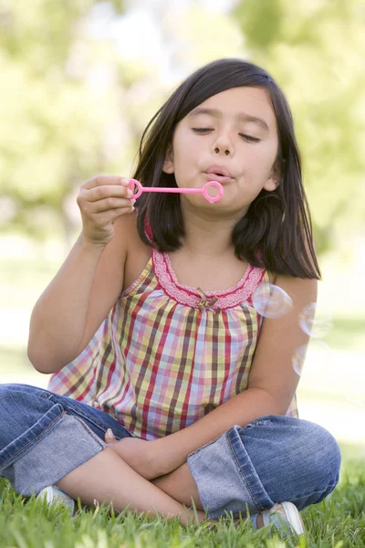 Chica joven soplando burbujas al aire libre — Foto de Stock