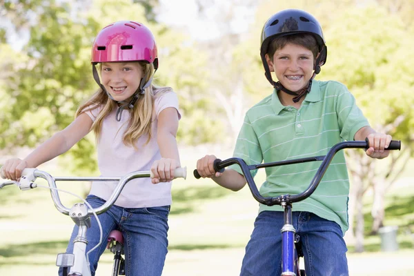 Брат и сестра на улице на велосипедах улыбаются — стоковое фото