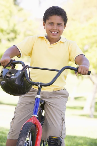 Jonge jongen op fiets buitenshuis glimlachen — Stockfoto