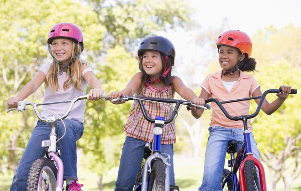 Tre giovani amiche all'aperto su biciclette sorridenti — Foto Stock