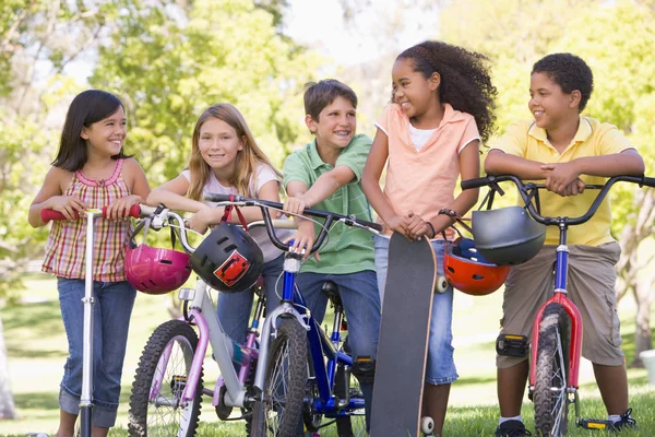 Cinco jovens amigos com bicicletas scooters e skate ao ar livre — Fotografia de Stock