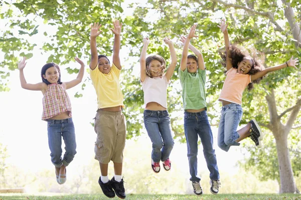 Five Young Friends Jumping Outdoors Smiling — Stock Photo, Image