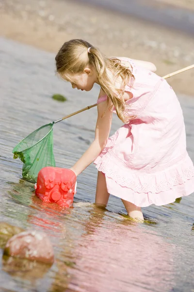 Chica joven en la playa con red y cubo — Foto de Stock
