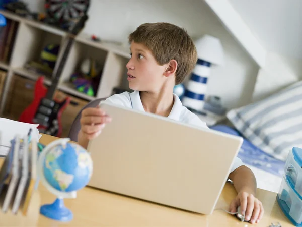 Fiatal fiú használ egy laptop, a hálószobában — Stock Fotó