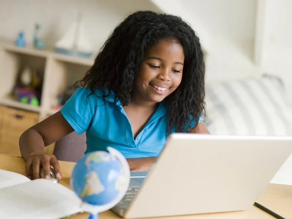 Ung flicka gör sina läxor på en bärbar dator — Stockfoto