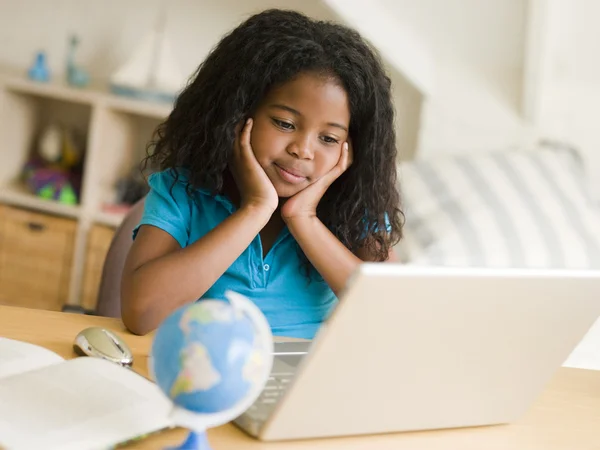 Mladá dívka dělá si úkoly na laptop — Stock fotografie