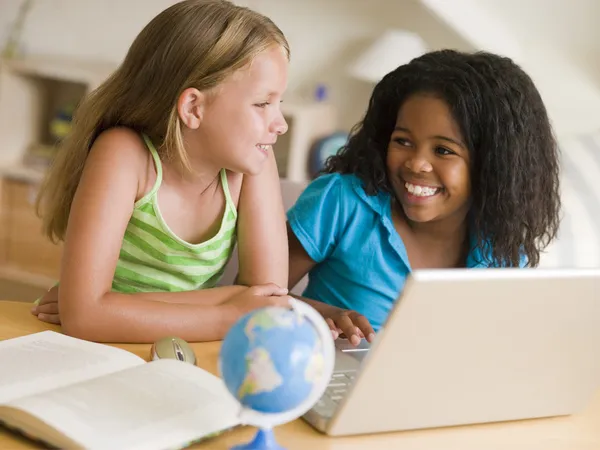 Zwei junge Mädchen machen ihre Hausaufgaben auf einem Laptop — Stockfoto