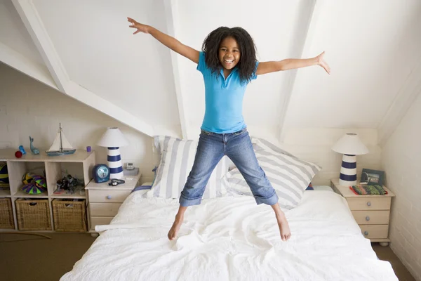 Junges Mädchen springt auf ihr Bett — Stockfoto