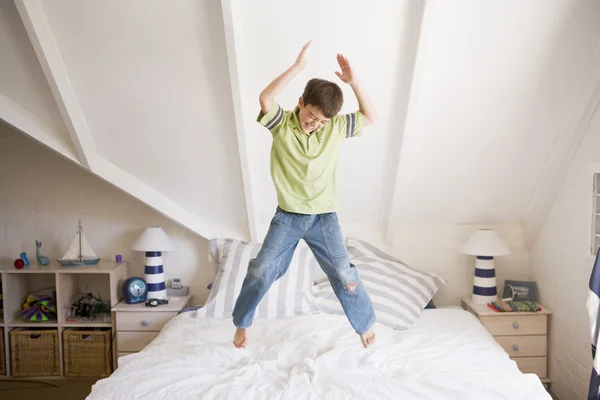 Junge springt auf sein Bett — Stockfoto