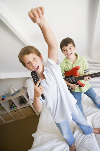 人の男の子はベッドの上に立って ギターを演奏し 歌うにはハ — ストック写真