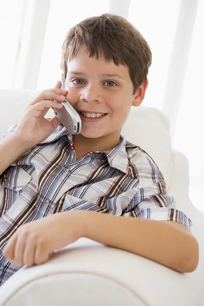 Νεαρό αγόρι κάθεται σε έναν καναπέ, μιλάμε για ένα κινητό τηλέφωνο — Φωτογραφία Αρχείου