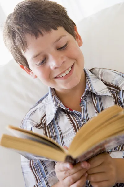 Mladý chlapec seděl na pohovce, čtení knihy — Stock fotografie