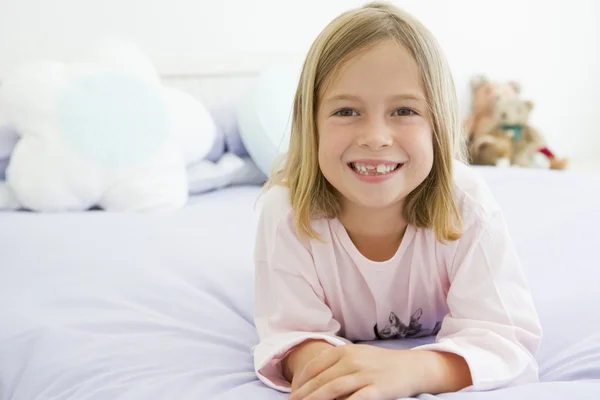 彼女はパジャマ姿で彼女のベッドに横になっている若い女の子 — ストック写真