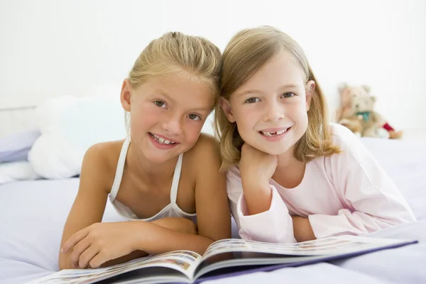 Zwei junge Mädchen im Schlafanzug, die ein Buch lesen — Stockfoto