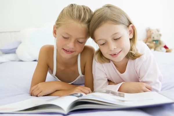 Två unga tjejer i sin pyjamas, läsa en bok — Stockfoto