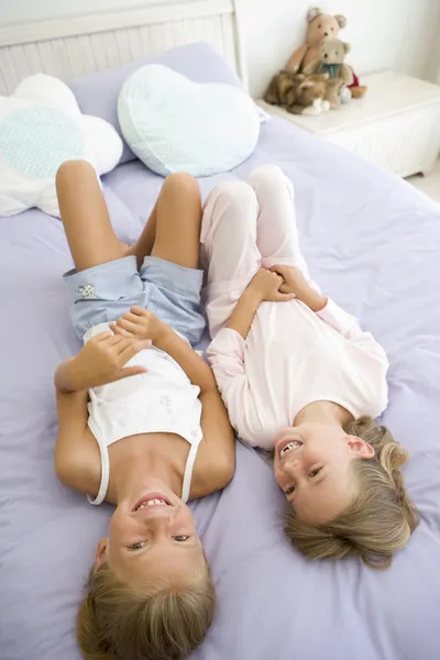 Zwei junge Mädchen im Schlafanzug auf einem Bett liegend — Stockfoto