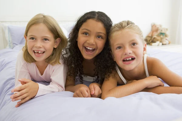 三个年轻女孩躺在他们的睡衣床上 — 图库照片