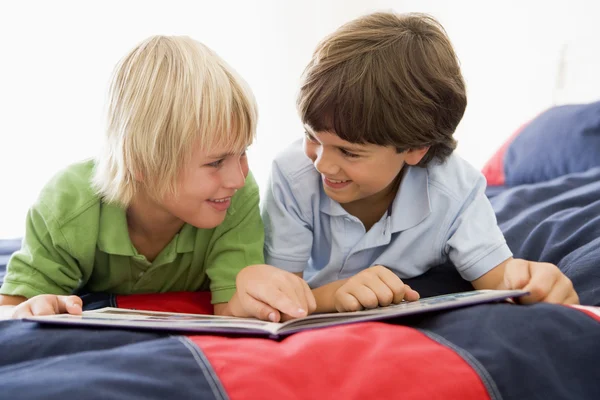 Due giovani ragazzi sdraiati su un letto a leggere un libro — Foto Stock