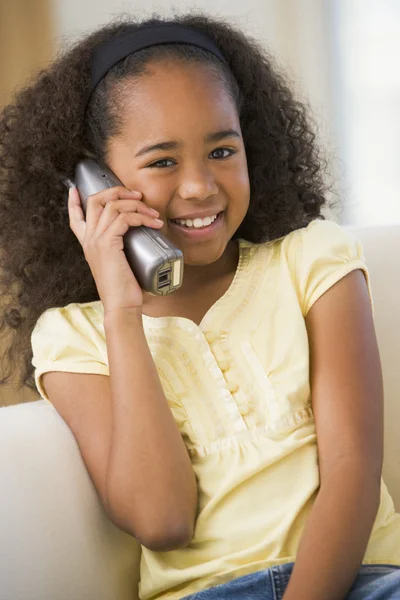 Ung flicka sitter på en soffa, talar i telefon — Stockfoto
