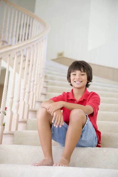 Ung pojke sitter på ett trapphus hemma — Stockfoto