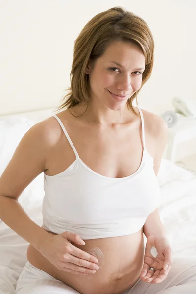 Hamile Kadın Gülümseyerek Göbek Üzerinde Yatak Sürtünme Krem — Stok fotoğraf