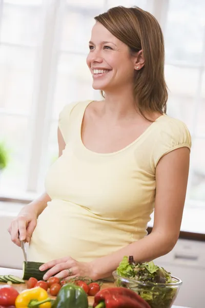 サラダの笑顔を作って台所で妊娠中の女性 — ストック写真