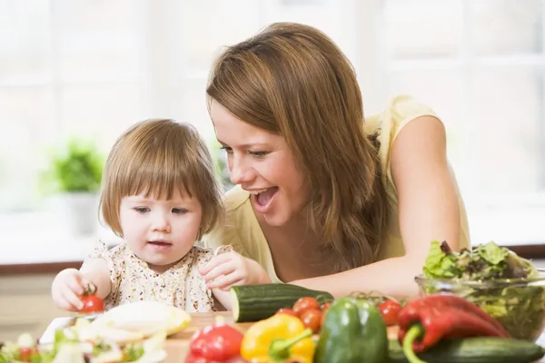 Mother and daughter in kitchen making a salad smiling — Stock Photo, Image