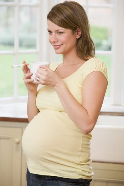 怀孕的女人站在咖啡和香烟 Smi 的厨房 — 图库照片