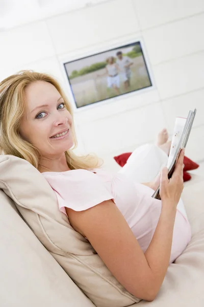 孕妇阅读杂志与电视在背景 — 图库照片