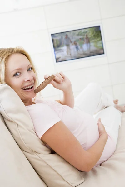 Έγκυος Γυναίκα Μπροστά Στην Τηλεόραση Και Τρώει Σοκολάτα Χαμογελώντας — Φωτογραφία Αρχείου