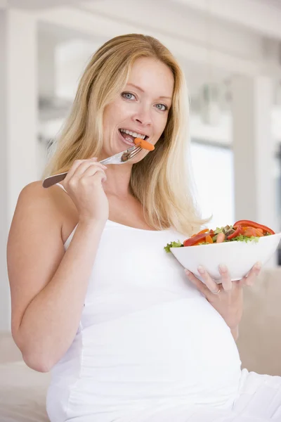 Беременная женщина с чашей салата улыбается — стоковое фото