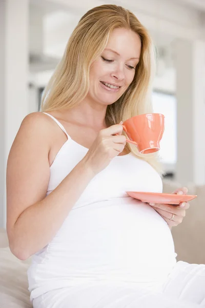 笑みを浮かべて紅茶のカップと妊娠中の女性 — ストック写真