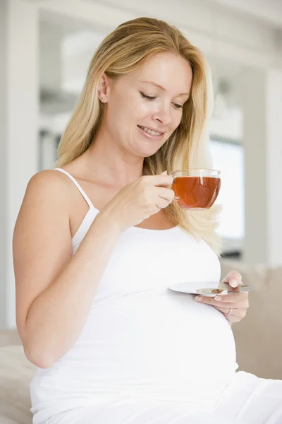 Беременная женщина с чашкой чая улыбается — стоковое фото