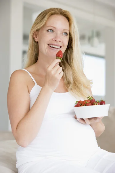 Kobieta w ciąży z miska truskawek uśmiechający się — Zdjęcie stockowe
