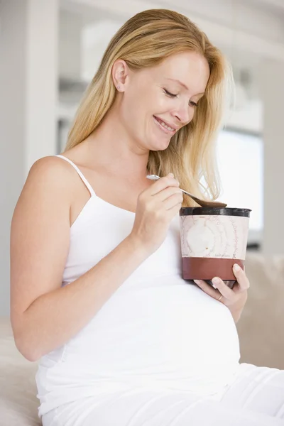 Беременная женщина с ведром мороженого улыбается — стоковое фото