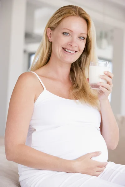 Беременная женщина со стаканом молока улыбается — стоковое фото