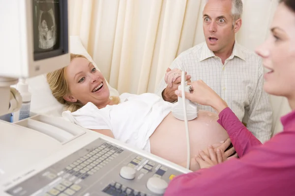 Беременная женщина получает ультразвук от врача с мужем часы — стоковое фото