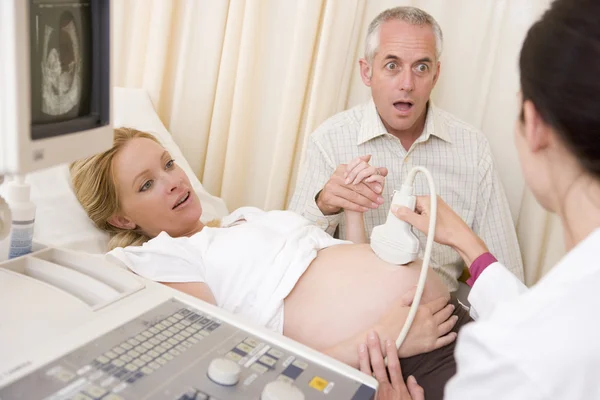 Беременная женщина получает ультразвук от врача с мужем часы — стоковое фото