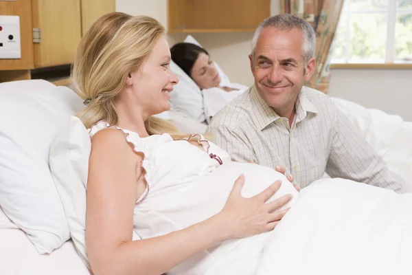 Hamile kadın kocasıyla gülümseyen hastane içinde — Stok fotoğraf