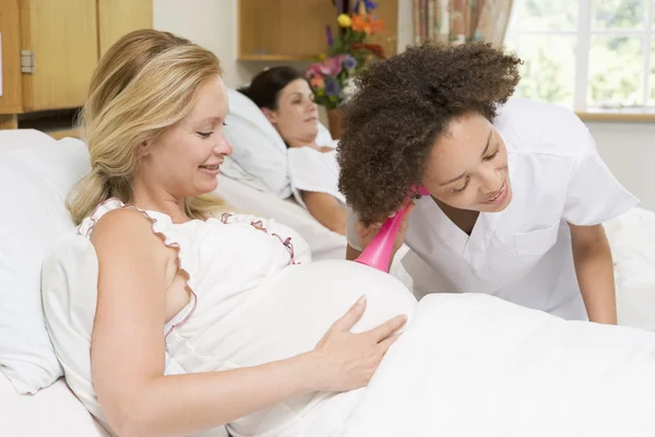 Enfermera revisando el vientre de la mujer embarazada y sonriendo — Foto de Stock