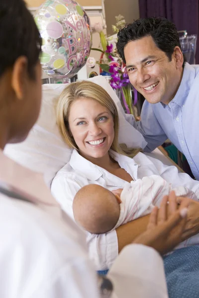 Nieuwe ouders met baby praten met arts en glimlachen — Stockfoto