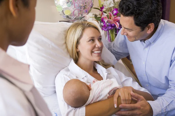 Novos pais com bebê conversando com médico e sorrindo — Fotografia de Stock