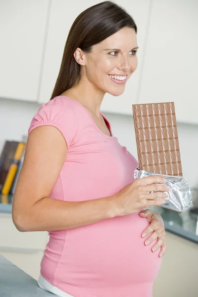 怀孕的女人在厨房里与微笑大型巧克力 — 图库照片