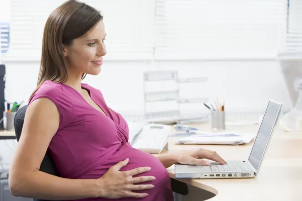 Беременная женщина на работе с — стоковое фото