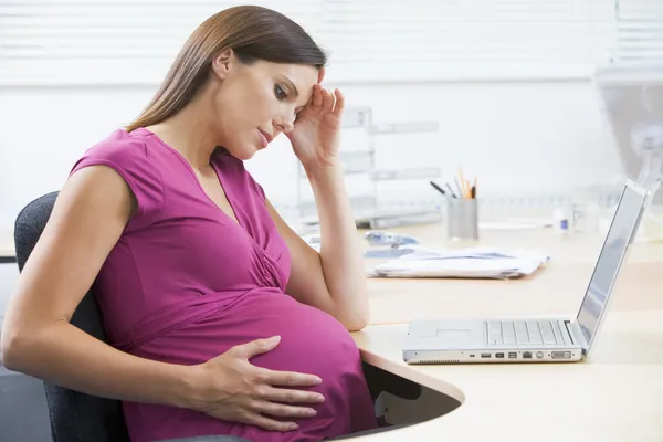 Zwangere vrouw op het werk met laptop op zoek benadrukt — Stockfoto