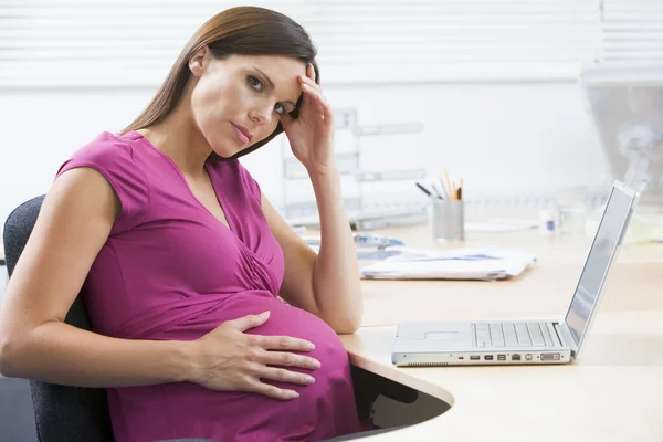 Schwangere bei der Arbeit mit Laptop sieht gestresst aus — Stockfoto