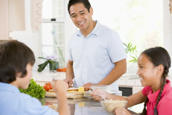 Barn som äter frukost medan pappa förbereder mat — Stockfoto